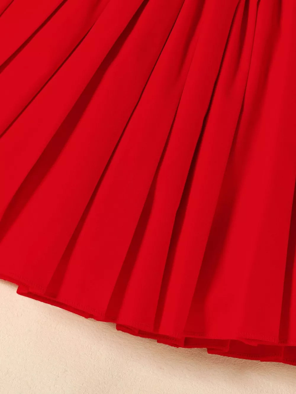 Red toddler outfit skirt with pleats and a ruffled hem.