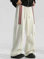 Men's cream loose-fit sweatpants with red side stripes and drawstring.