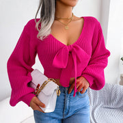 Fuchsia ribbed knit crop top with V-neck and bow front, long balloon sleeves.