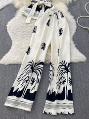 Tropical print two-piece set with belted detail, featuring wide-leg pants and a tie-front top in white with black palm tree
