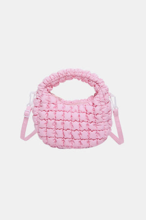 Pink padded crescent crossbody bag with sculptural texture and ruched handle