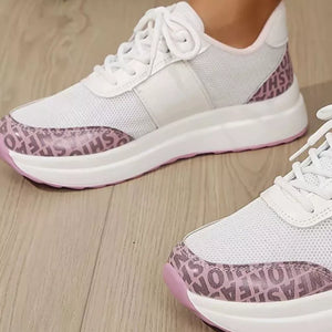 White lace-up sneakers with pink fashion print detailing and white mesh panels.