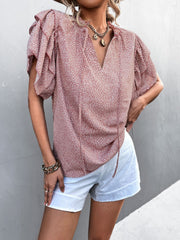 Pink ditsy print blouse with ruffle sleeves and tie neck, styled with white shorts.