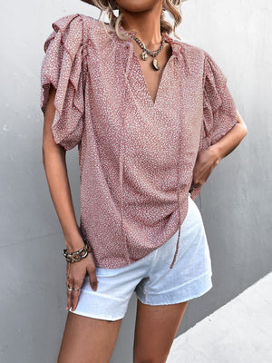 Pink ditsy print blouse with ruffle sleeves and tie neck, styled with white shorts.