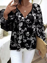 Black embroidered sheer long-sleeve blouse with button detail and floral pattern.