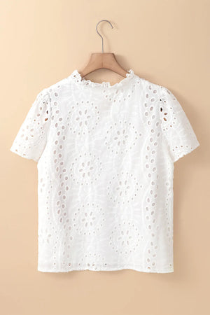 White embroidered eyelet blouse with short sleeves and ruffled mock neck.