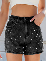 Black studded denim high-waisted cutoff shorts with a distressed hem.