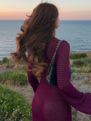 Plum purple knit maxi dress with bell sleeves and a sheer texture, worn with a black quilted bag.