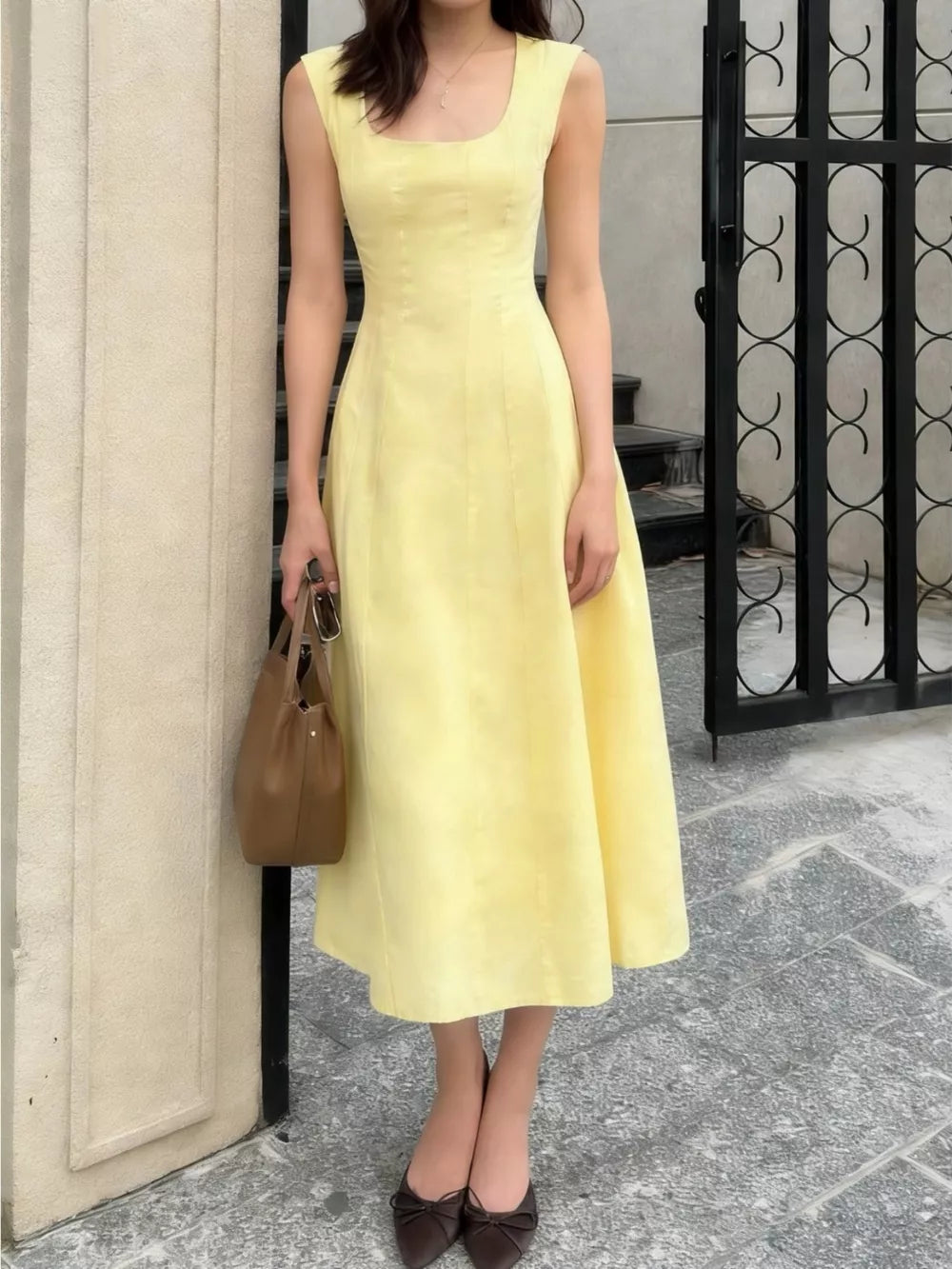 Sleeveless yellow a-line midi dress with square neckline and subtle seams.