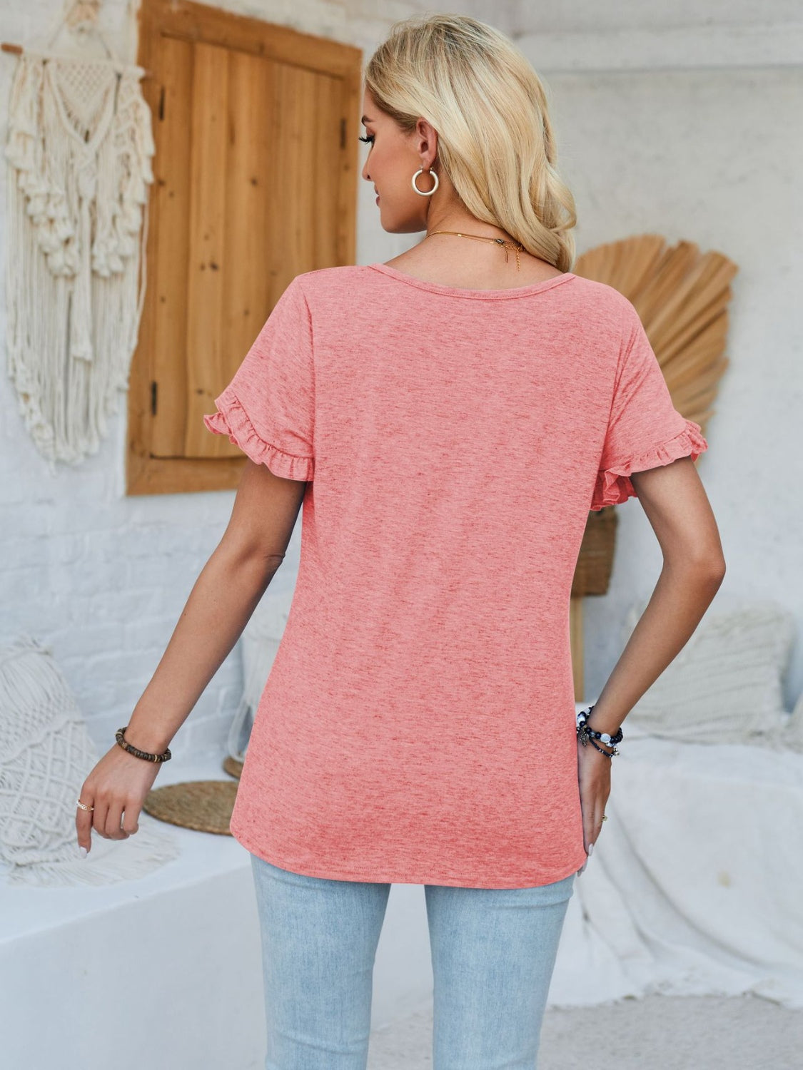 Coral tee with flutter sleeves and a scoop neck, styled with light wash jeans.