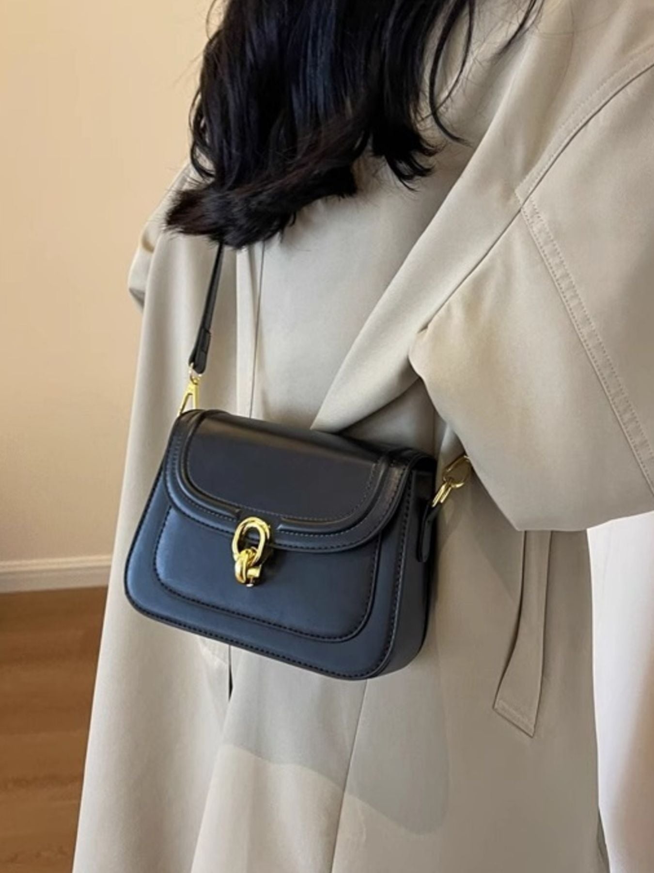 Black pu leather flap crossbody bag with gold hardware and a turn-lock closure.