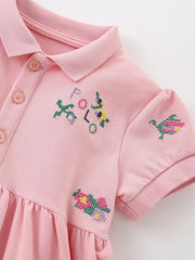 Pink cotton blend polo dress with embroidered flowers and letters.