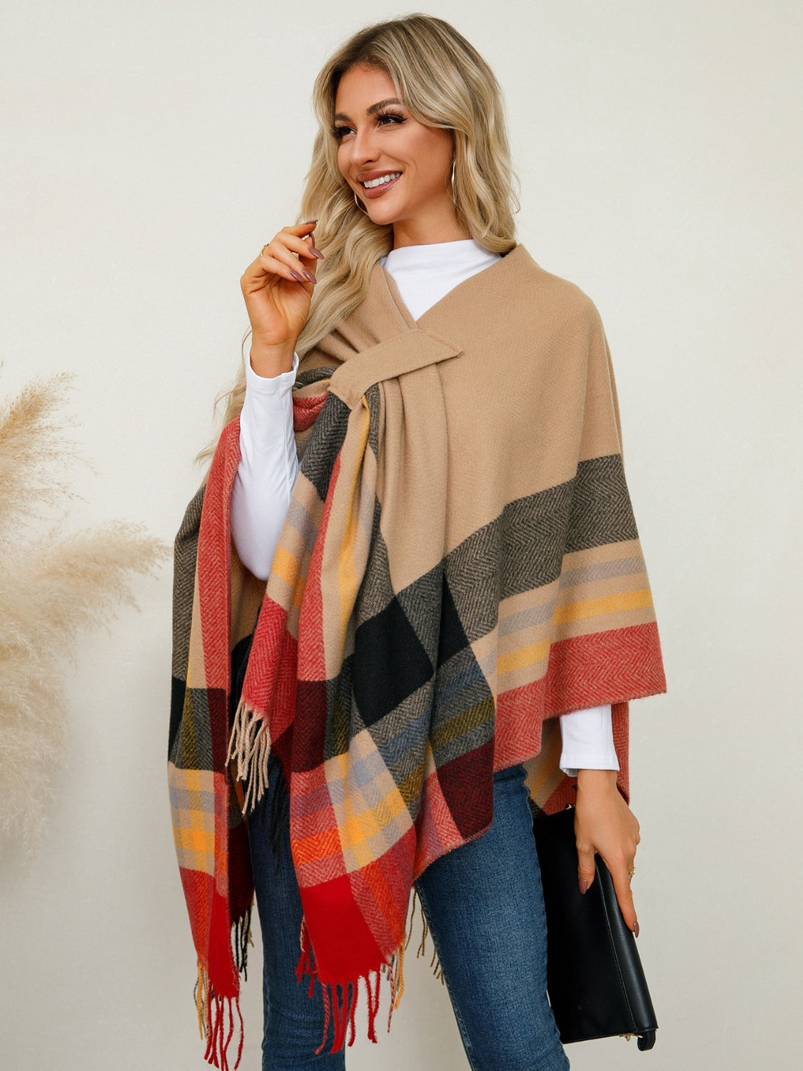 Asymmetric plaid fringe cape in tan with red, black, yellow, and grey checkered pattern.