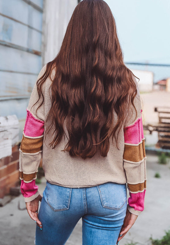 Beige knit sweater with color block sleeves in pink and brown.