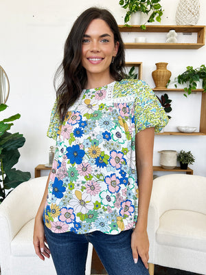 Floral patchwork puff sleeve blouse with lace trim and round neckline.