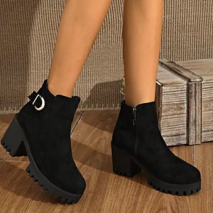 Black suede ankle boots with round toe, block heel, and decorative buckle detail.