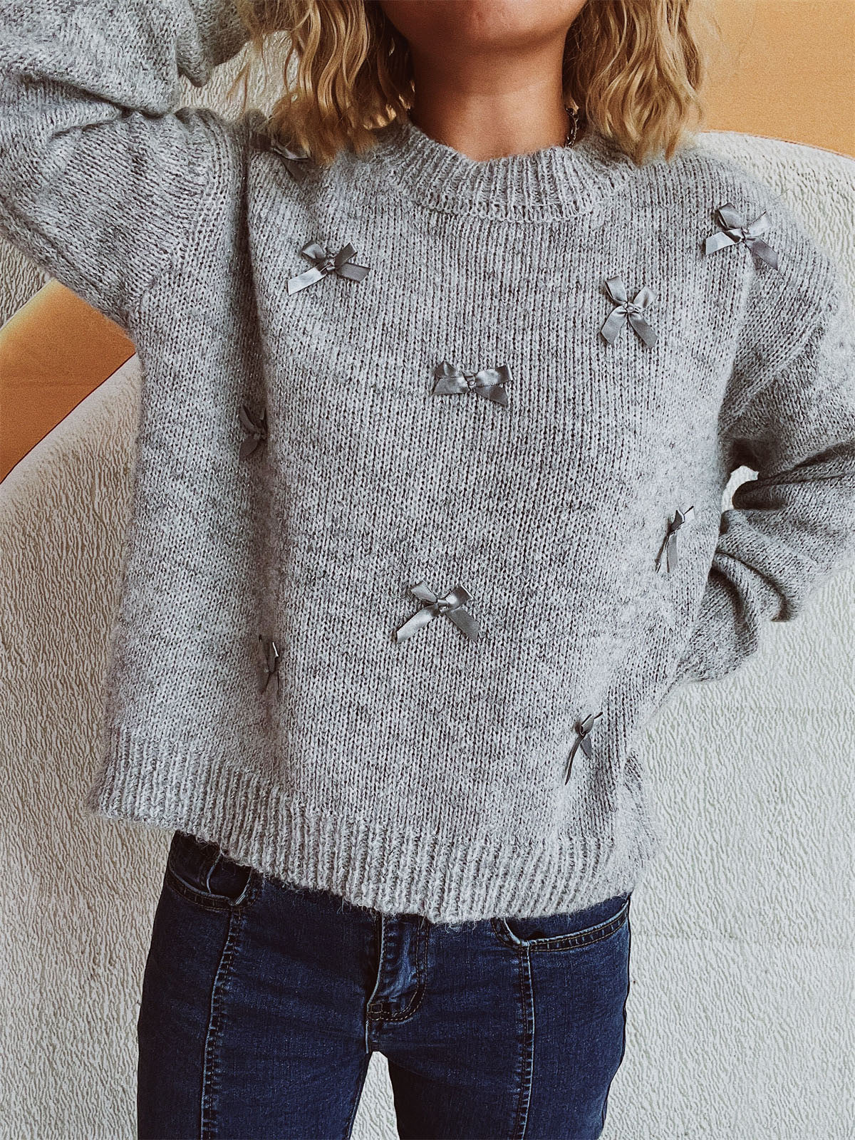 Gray knit crewneck sweater with scattered satin bows.