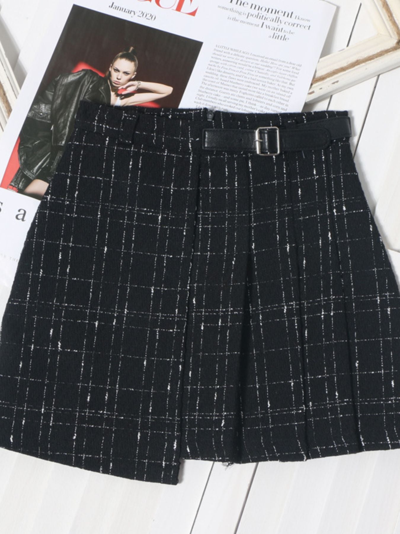 Black plaid mini skirt with a belted waist and asymmetrical hem.