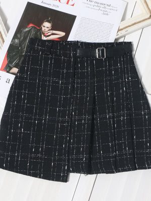 Black plaid mini skirt with a belted waist and asymmetrical hem.