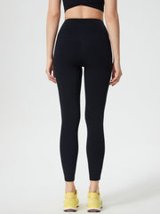 Black high-waisted leggings with contouring detail and pocket, worn with yellow sneakers.