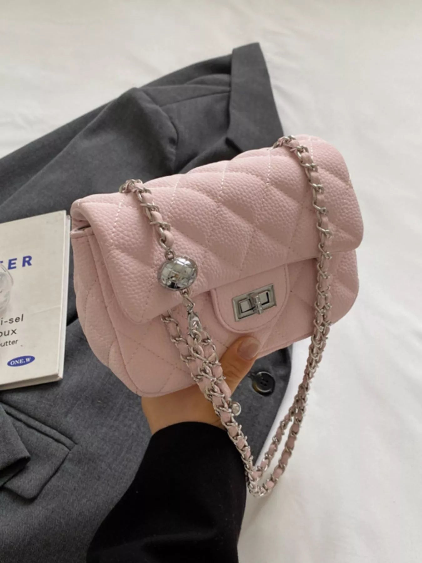 Pink quilted chain crossbody clutch with silver hardware and ball charm.