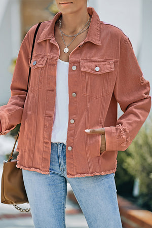 Salmon distressed denim trucker jacket with frayed edges and distressed details on sleeves.