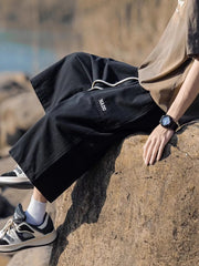 Black relaxed fit cropped sweatpants with drawstring and embroidered logo detail.