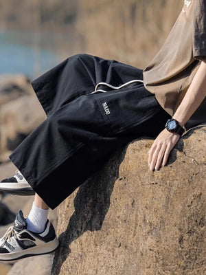 Black relaxed fit cropped sweatpants with drawstring and embroidered logo detail.