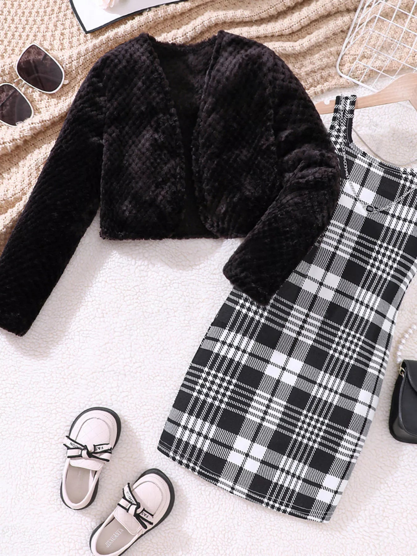 Black fuzzy cardigan with long sleeves and a plaid dress.