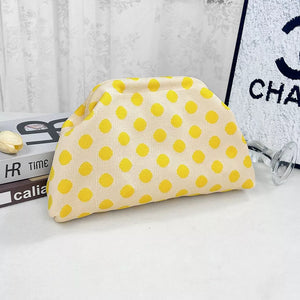 Yellow polka dot knit clutch bag with a curved top and structured base.