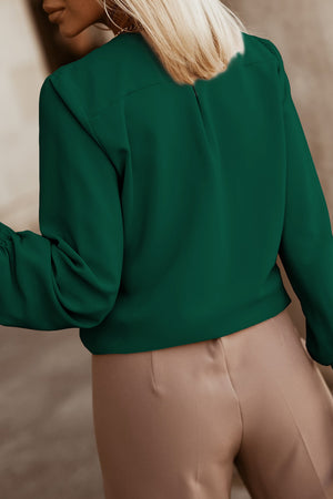 Green pleated yoke blouse with button detail and gathered sleeves.