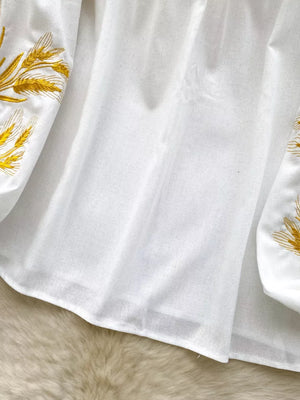 White embroidered tie-neck folk blouse with wheat detail on sleeves.