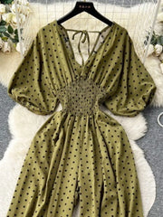 Army green polka dot smocked wide-leg romper with tie-back V-neck and puff sleeves.