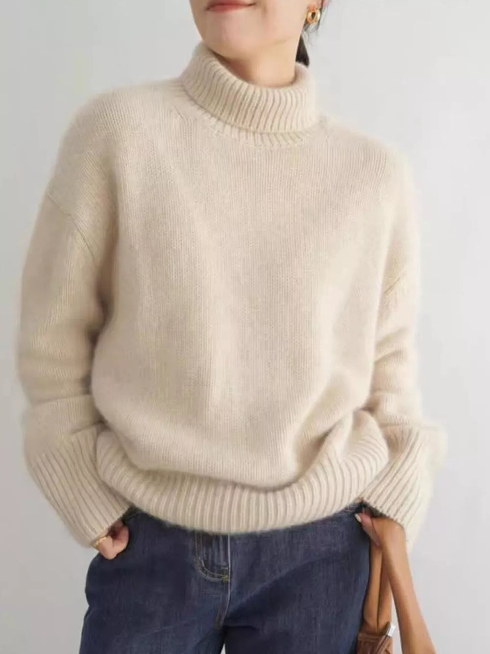 Cozy apricot acrylic turtleneck sweater with dropped shoulders and ribbed cuffs.