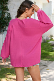 Fuchsia pink waffle knit blouson sleeve top with crewneck and cuffed sleeves.
