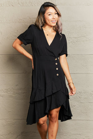 Black viscose wrap dress with button detail and asymmetric ruffled hemline