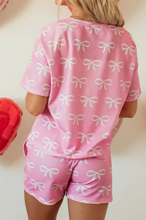 Pink ribbed loungewear set with allover white bow print, short sleeves and shorts.