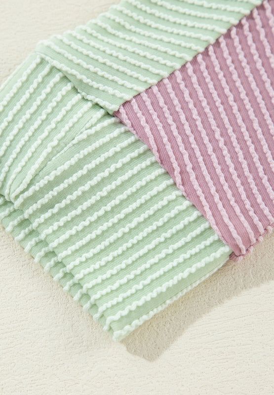 Waffle knit shirt with colorblock pattern in dusty pink and green with textured stripes.