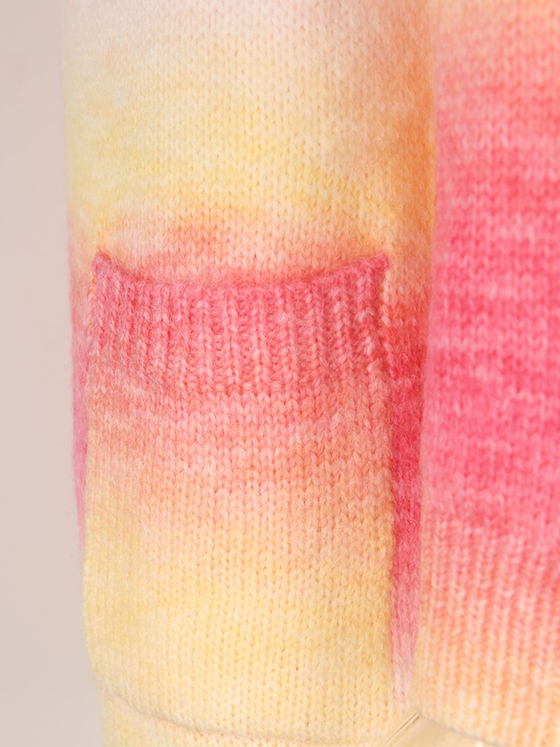 Knit cardigan with rainbow gradient in pink and yellow, featuring a pocket detail.