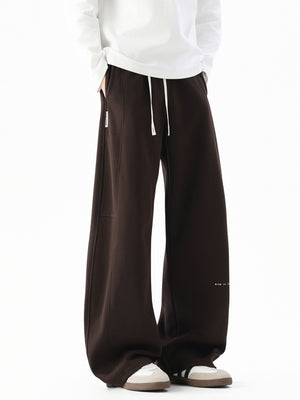 Men's dark coffee casual drawstring pants with wide leg and subtle logo detail.