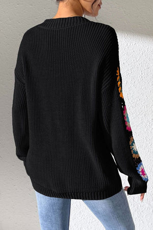 Black knit sweater with colorful granny square sleeves.