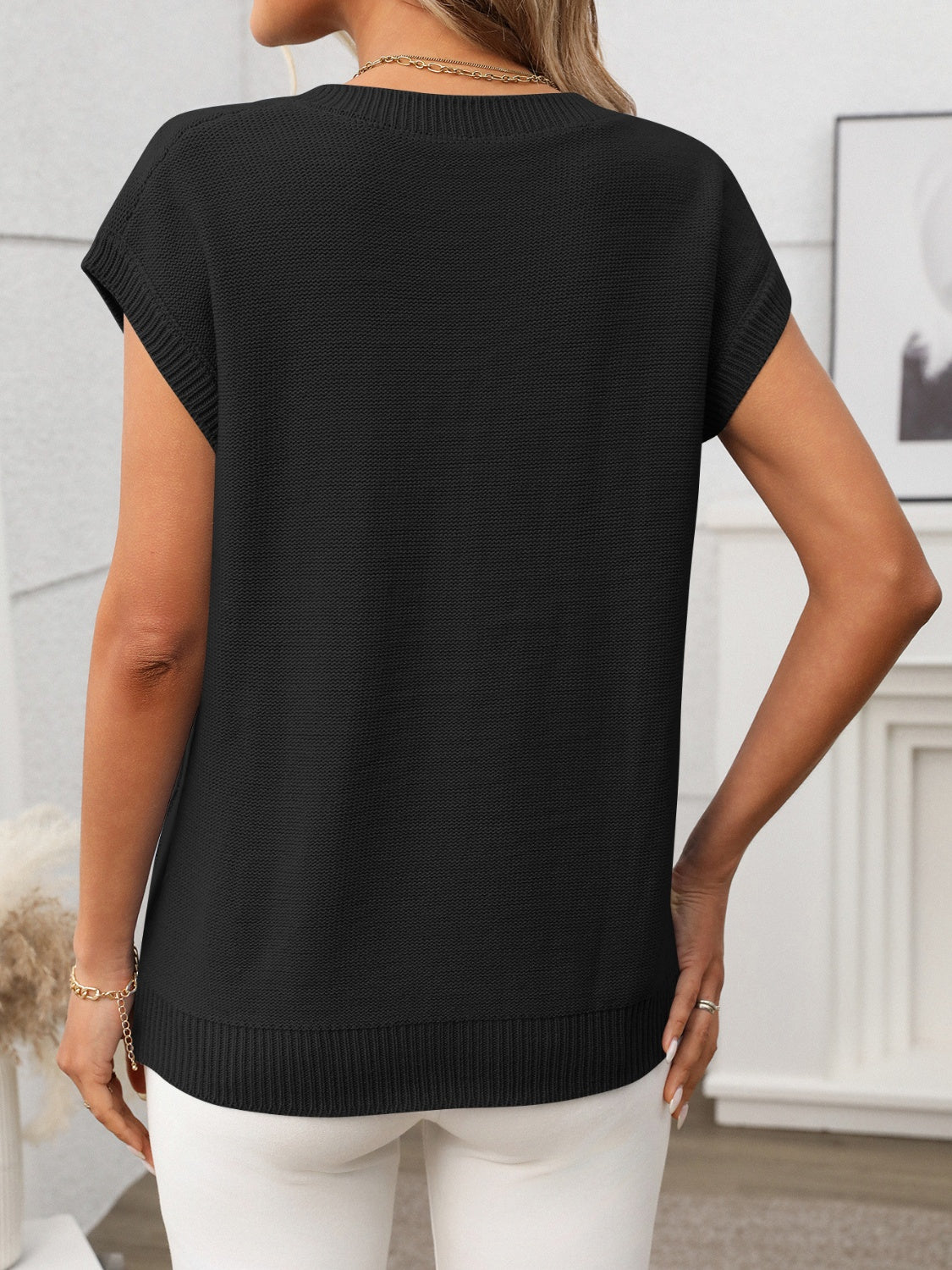 Black cable knit vest with V-neck and short sleeves, ribbed hem detail.