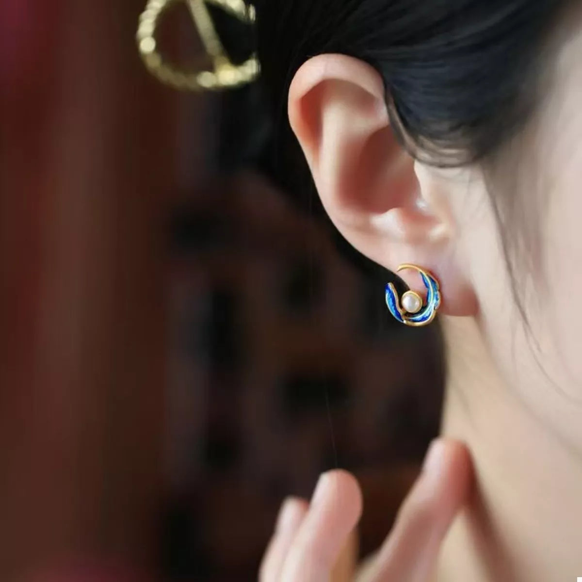 Elegant pearl feather earrings in blue and gold feature a pearl accent.