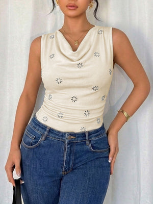 Cream cowl neck sleeveless bodysuit with allover floral print, styled with jeans.