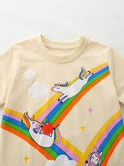 Cream cotton t-shirt with playful unicorns on a rainbow graphic, clouds, and stars.