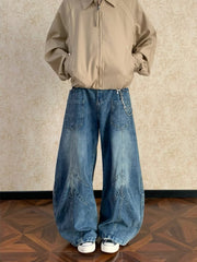 Men's blue washed wide-leg jeans with chevron stitching and chain detail.