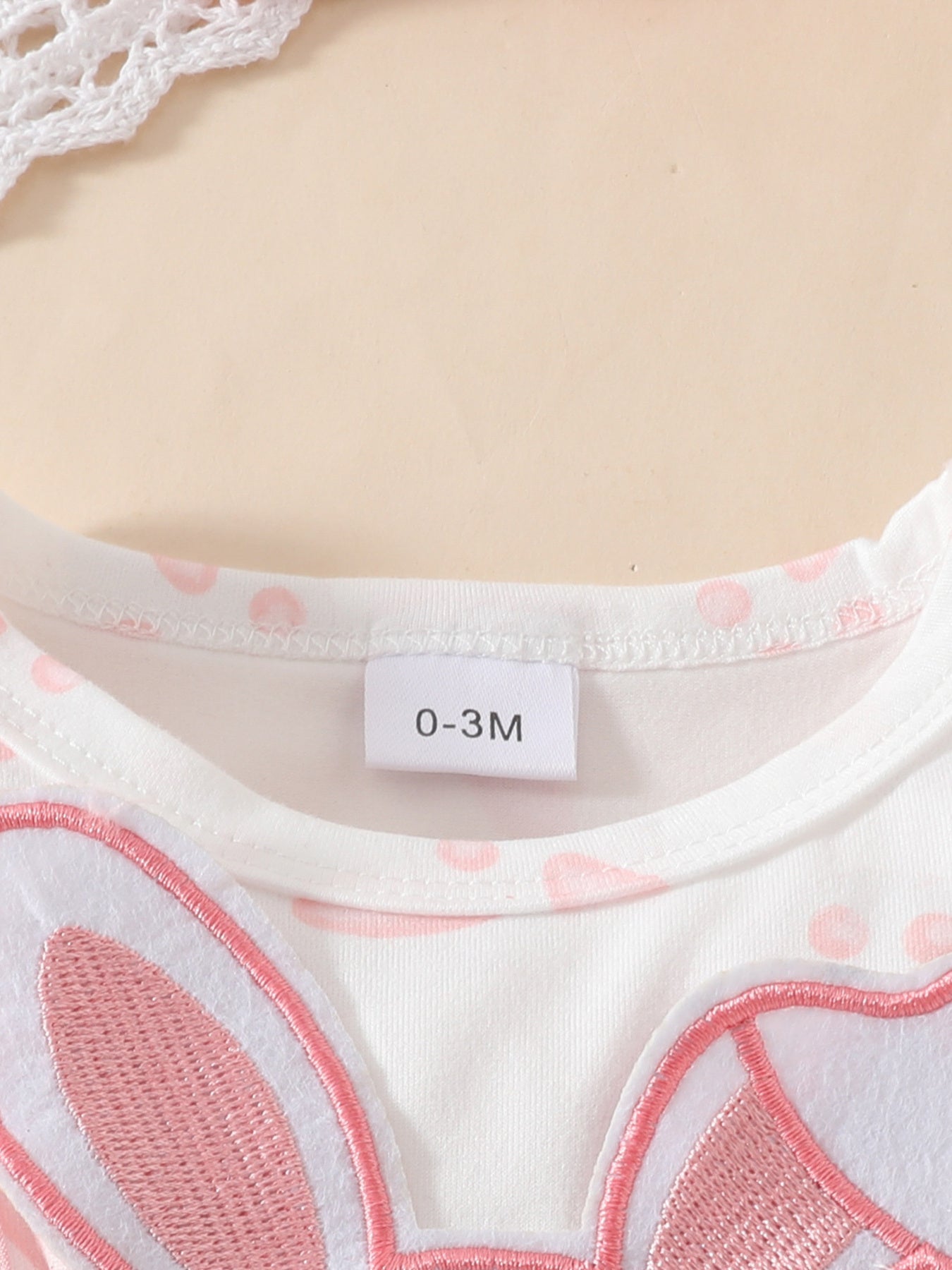 White baby dress with pink polka dots and a pink bunny applique detail.