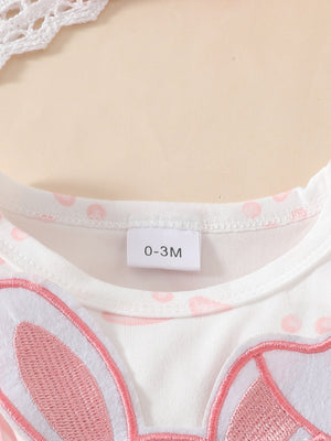 White baby dress with pink polka dots and a pink bunny applique detail.