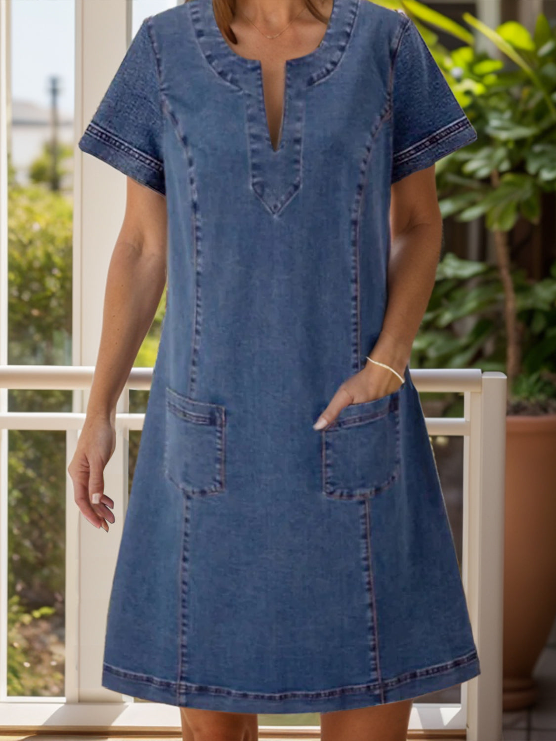 Denim trapeze dress in dusty blue with V-neck and patch pockets.