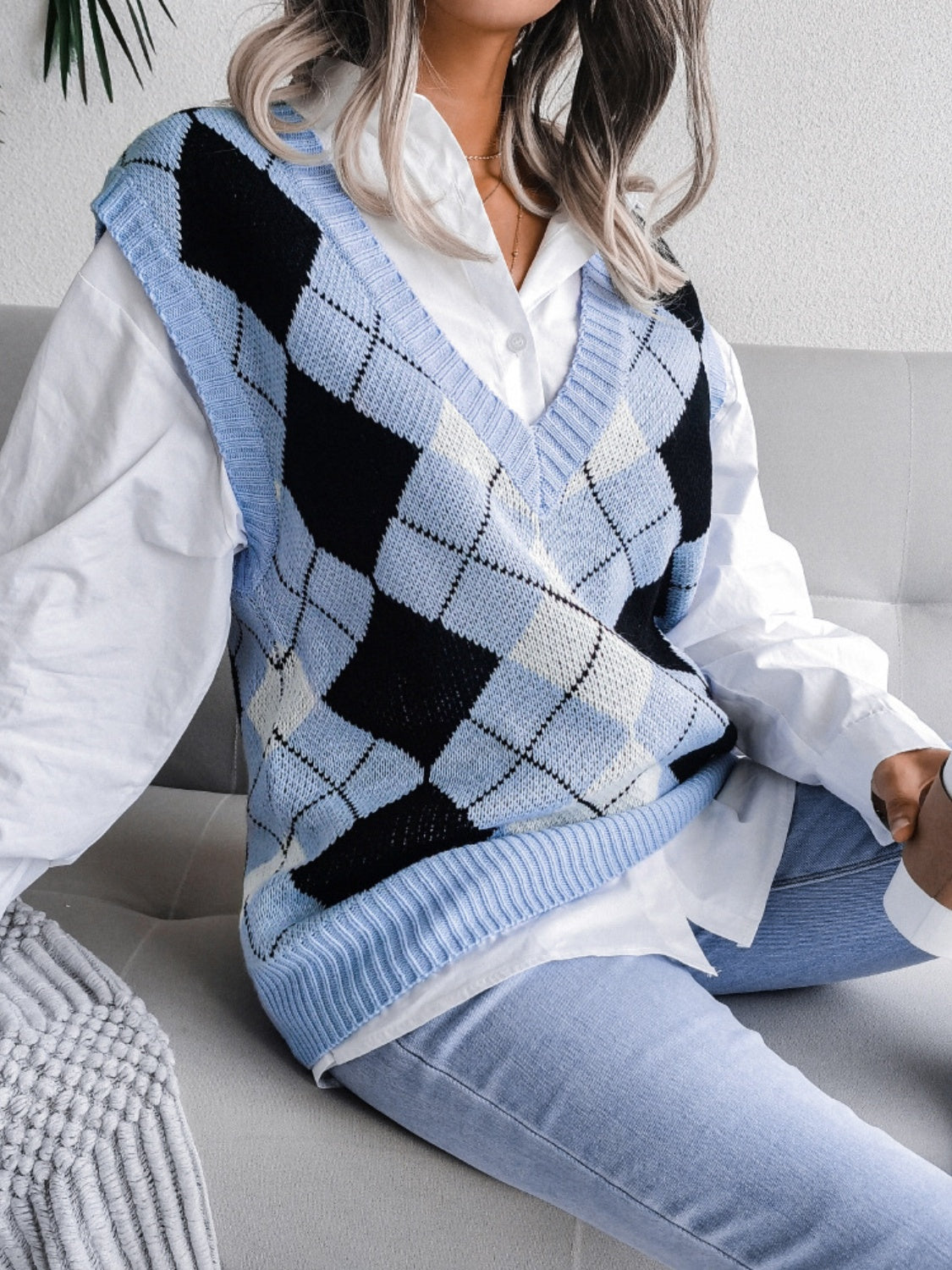 Argyle knit v-neck sweater vest in light blue, black, and white, styled over a white shirt.